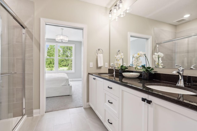 bathroom with a shower with door, dual bowl vanity, and tile patterned flooring