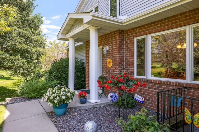 view of exterior entry with covered porch and brick siding