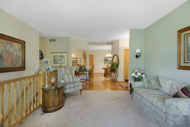 living area with carpet flooring, visible vents, and an inviting chandelier