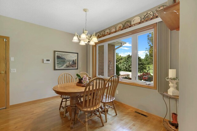 dining area featuring visible vents, light wood-style flooring, and an inviting chandelier