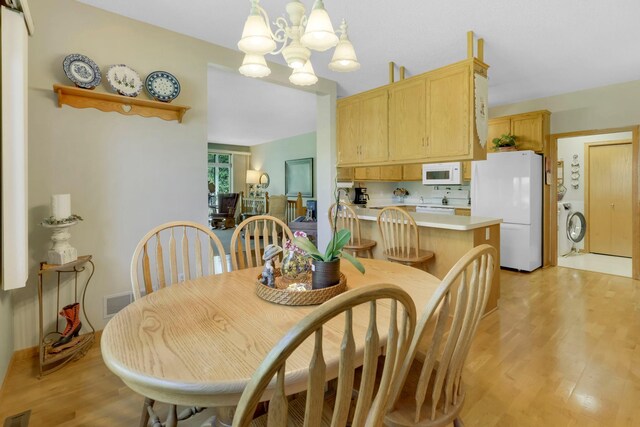 dining area with washer / dryer, light wood-type flooring, visible vents, and a notable chandelier