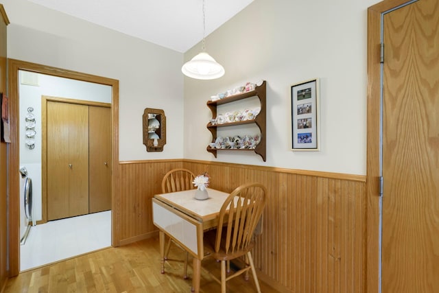 dining space with wooden walls, wainscoting, lofted ceiling, wood finished floors, and independent washer and dryer