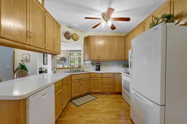 kitchen with light countertops, white appliances, a sink, and light wood-style flooring