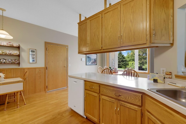 kitchen featuring pendant lighting, light countertops, wainscoting, white dishwasher, and light wood-type flooring