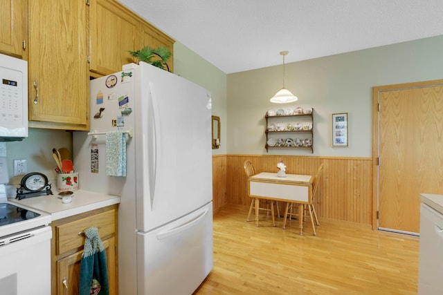 kitchen with light countertops, white appliances, wainscoting, and light wood finished floors