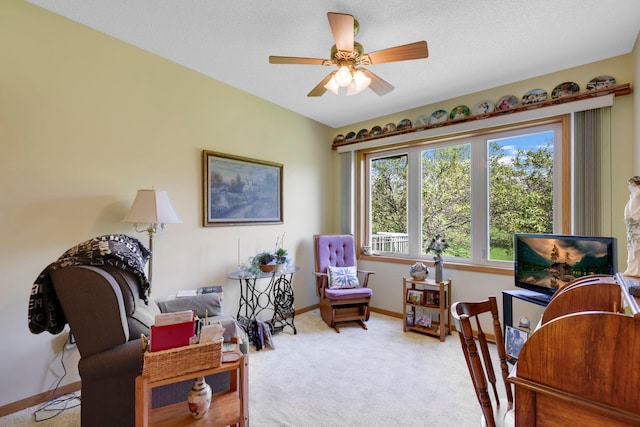 sitting room featuring carpet, baseboards, and a ceiling fan