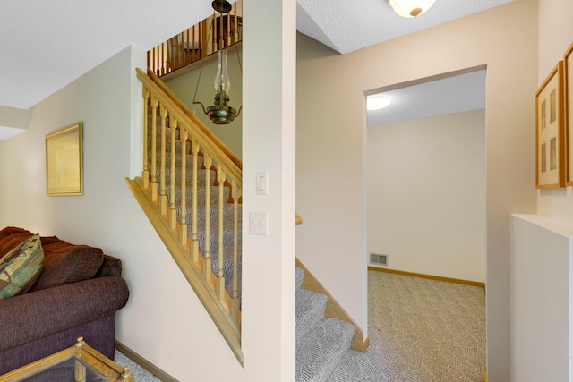 stairway featuring carpet flooring, visible vents, baseboards, and a textured ceiling