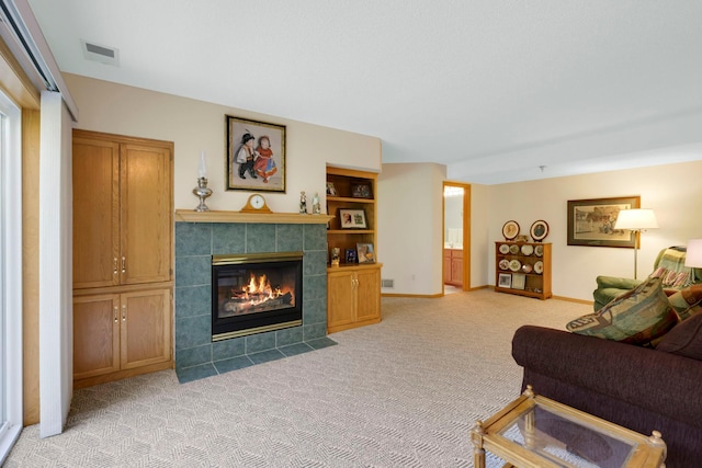 living area featuring built in features, a fireplace, light colored carpet, visible vents, and baseboards