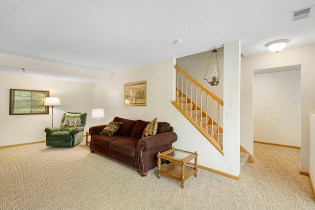 carpeted living area featuring stairway, baseboards, visible vents, and a textured ceiling