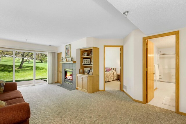 living room with a fireplace, baseboards, a textured ceiling, and light colored carpet