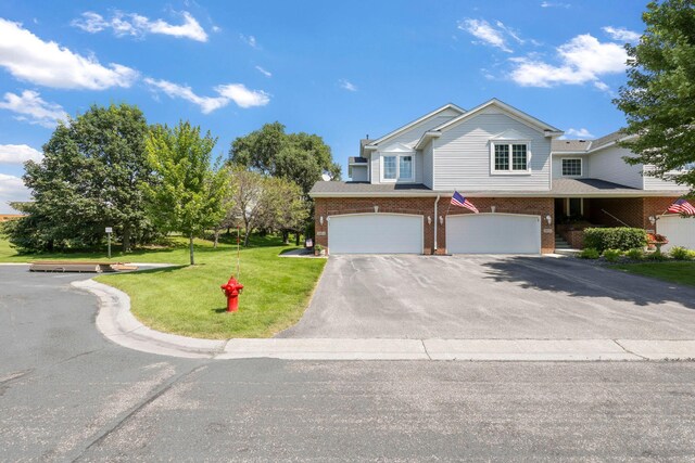 view of front of home featuring a garage, driveway, brick siding, and a front yard