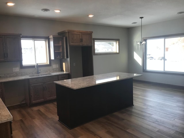 kitchen with light stone countertops, sink, decorative light fixtures, and a healthy amount of sunlight