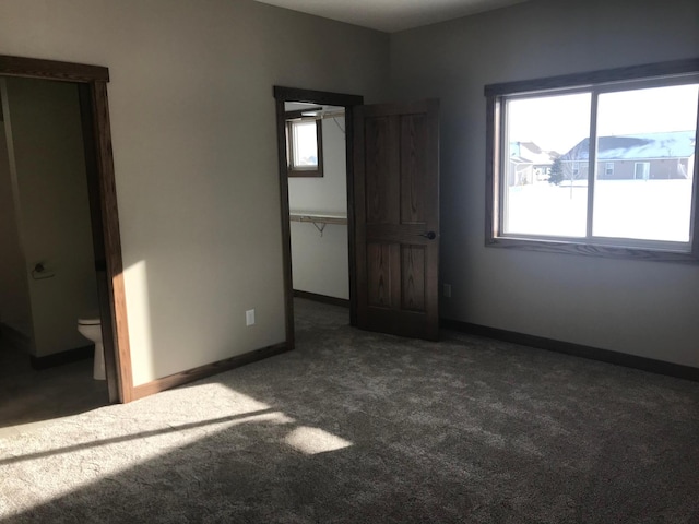 unfurnished bedroom with dark carpet and ensuite bath