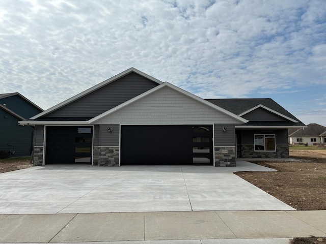 craftsman-style home with a garage, stone siding, and concrete driveway