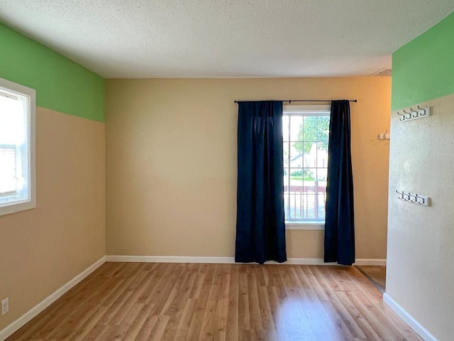 spare room with a textured ceiling and light hardwood / wood-style flooring