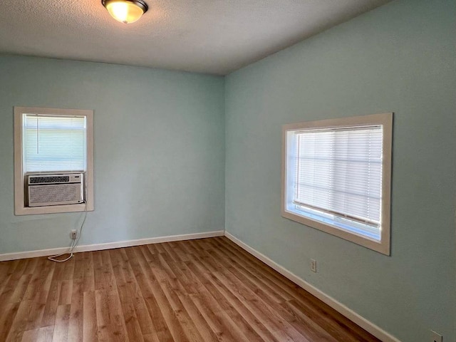 spare room with cooling unit, hardwood / wood-style floors, and a textured ceiling