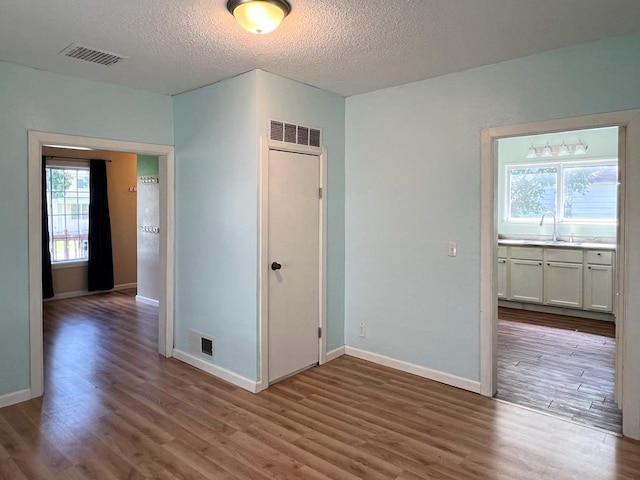 unfurnished bedroom featuring a textured ceiling, hardwood / wood-style flooring, and sink