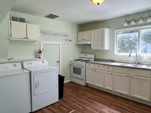 kitchen featuring white gas range oven, sink, dark hardwood / wood-style floors, white cabinetry, and washer and dryer