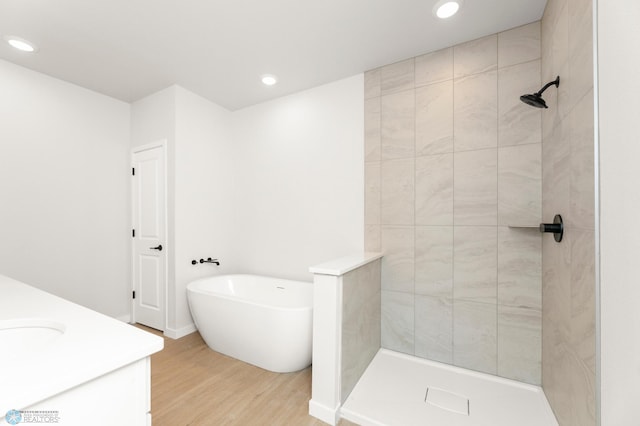 bathroom featuring wood-type flooring, shower with separate bathtub, and vanity