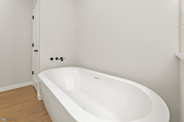 bathroom with wood-type flooring and a bath