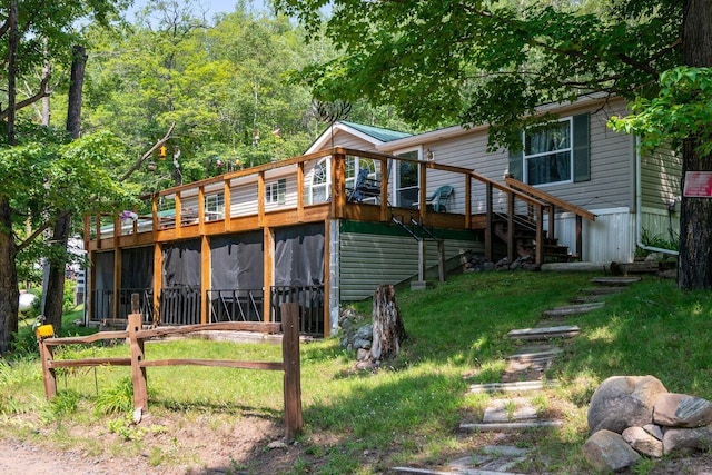 rear view of house featuring a wooden deck and a yard