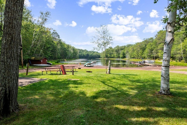 view of home's community with a water view, a view of trees, and a lawn