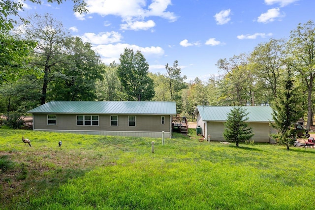 rear view of house with a lawn, metal roof, and a wooden deck