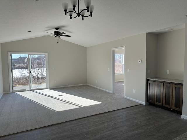 unfurnished living room with lofted ceiling, dark hardwood / wood-style floors, ceiling fan with notable chandelier, and a textured ceiling