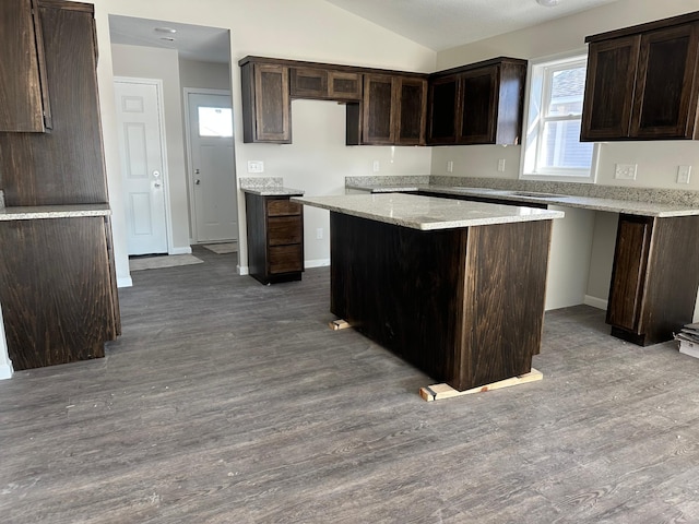 kitchen with hardwood / wood-style flooring, dark brown cabinetry, a center island, and vaulted ceiling