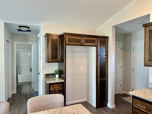 kitchen featuring dark wood finished floors, a textured ceiling, and dark brown cabinets