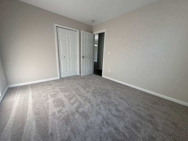 unfurnished bedroom featuring carpet floors, baseboards, and a closet