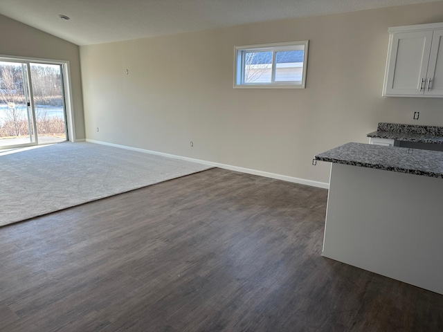 unfurnished dining area featuring a healthy amount of sunlight, baseboards, and lofted ceiling