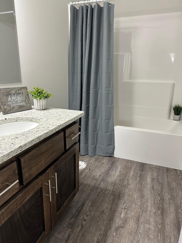 full bath featuring shower / bath combo with shower curtain, vanity, and wood finished floors