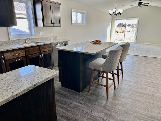 kitchen featuring a breakfast bar, dark wood-style flooring, dishwasher, and a sink