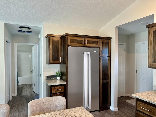 kitchen with dark wood-type flooring, freestanding refrigerator, and dark brown cabinetry