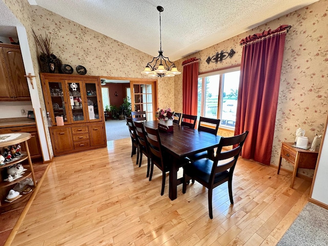 dining room with light hardwood / wood-style floors, a textured ceiling, and a chandelier