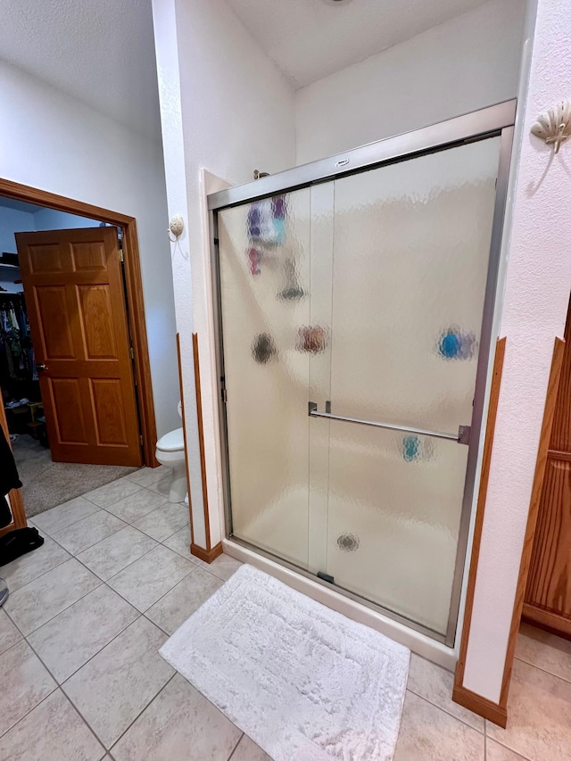 bathroom featuring toilet, walk in shower, and tile patterned flooring