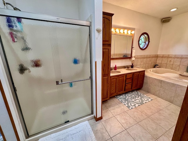 bathroom with tile patterned flooring, independent shower and bath, double sink vanity, and a textured ceiling