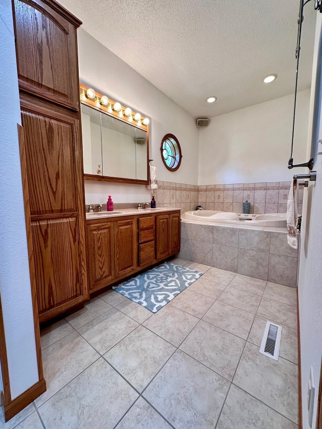 bathroom with tile patterned floors, a textured ceiling, a relaxing tiled tub, and dual vanity