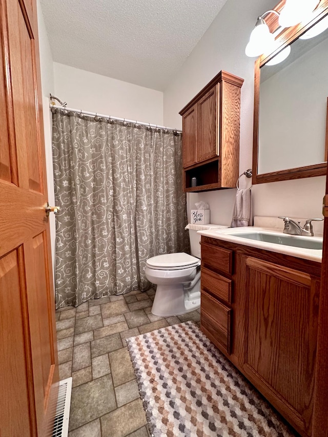 bathroom featuring tile patterned flooring, toilet, a textured ceiling, and vanity