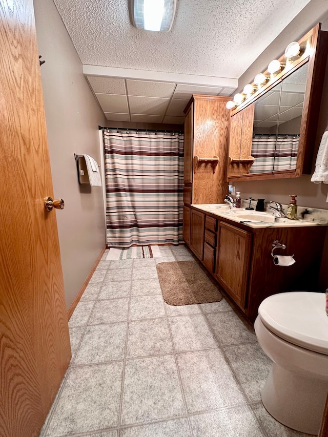 bathroom with tile patterned floors, vanity, a paneled ceiling, and toilet