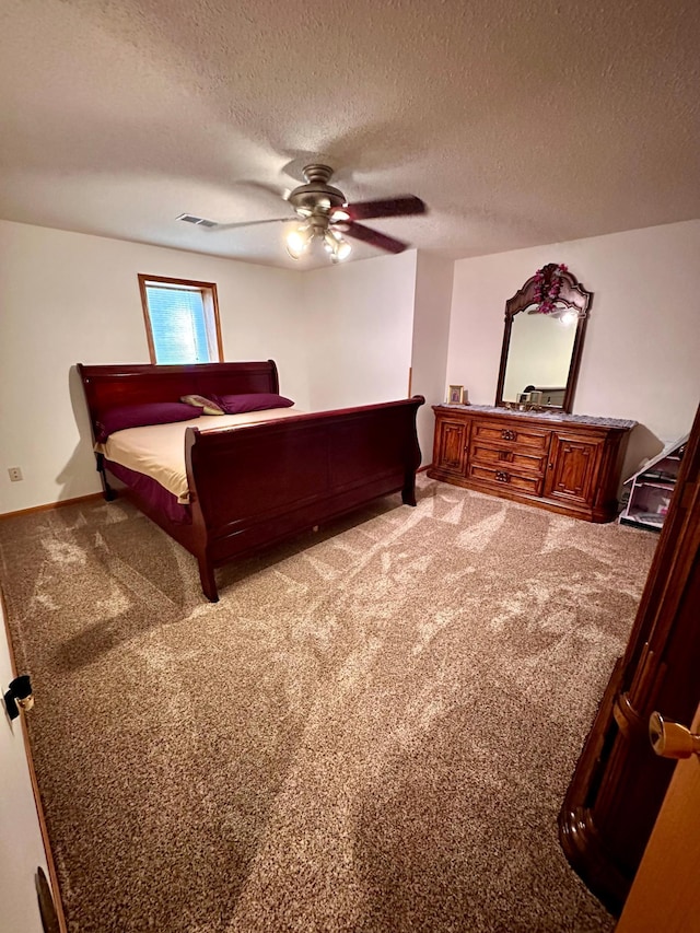 bedroom with ceiling fan, carpet floors, and a textured ceiling