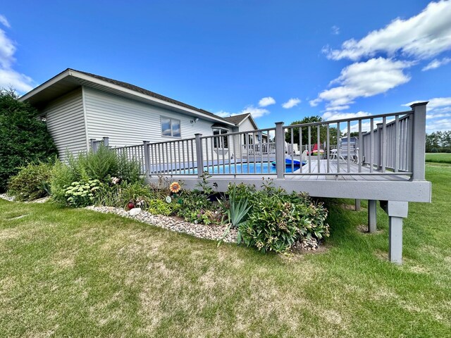 rear view of house featuring a lawn and a swimming pool side deck