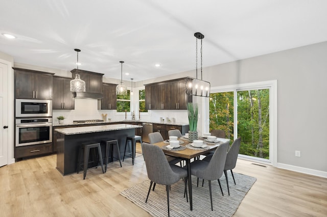 dining space featuring sink, light wood-type flooring, and plenty of natural light