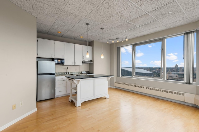 kitchen with light hardwood / wood-style floors, white cabinetry, track lighting, and stainless steel refrigerator