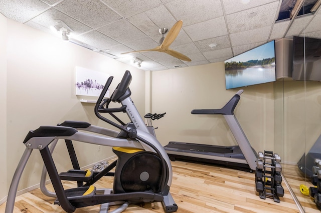 workout room featuring a drop ceiling, a water view, and hardwood / wood-style flooring