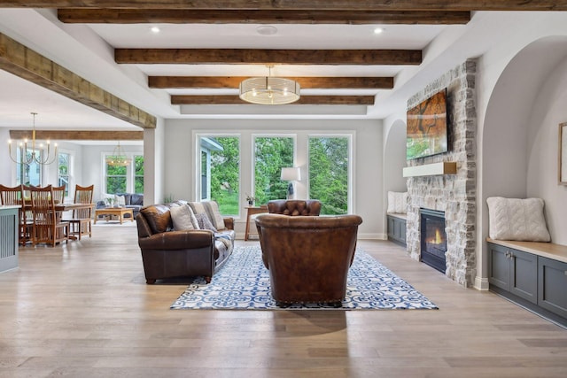 living room featuring beamed ceiling, light hardwood / wood-style floors, and a fireplace