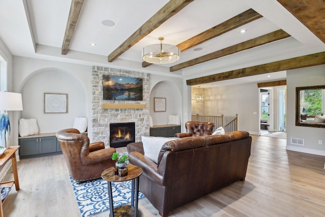 living room with a fireplace, light wood-type flooring, and beamed ceiling