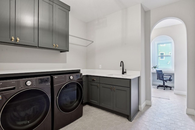 washroom featuring light tile patterned flooring, sink, washing machine and clothes dryer, and cabinets