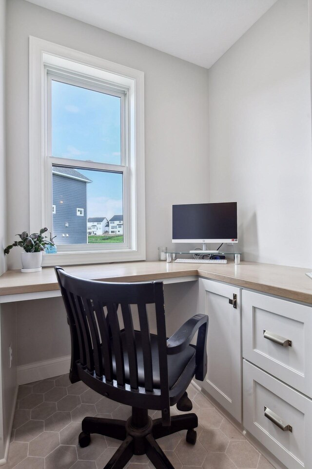 office space featuring a wealth of natural light, built in desk, and light tile patterned floors